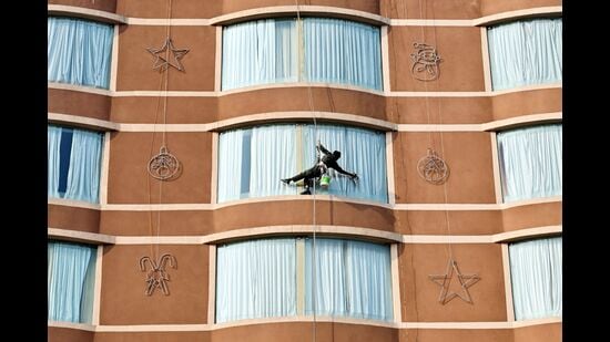 A labourer cleans a high rise window at a hotel in Amritsar on December 24, 2024. (Photo by Narinder NANU / AFP) (AFP)