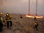 Firefighters take cover as a tornado hits while the Hughes Fire burns in Castaic Lake, California, U.S. January 22, 2025. REUTERS/David Swanson