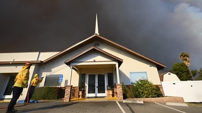 Private firefighters from Capstone Fire spray water on a church as the plume of smoke from the Hughes fire darkens the sky in Castaic, a northwestern part of Los Angeles, California. According to LA County Fire Chief Anthony Marrone, crews are gaining the upper hand, but the fire is still challenging to suppress. (AFP/Robyn Beck) Private firefighters from Capstone Fire spray water on a church as the plume of smoke from the Hughes fire darkens the sky in Castaic, a northwestern part of Los Angeles, California. According to LA County Fire Chief Anthony Marrone, crews are gaining the upper hand, but the fire is still challenging to suppress. (AFP/Robyn Beck)