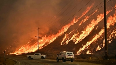 Emergency vehicles seen on the side of the road as flames from the Hughes Fire race up the hill in Castaic in Los Angeles, California. (AFP) Emergency vehicles seen on the side of the road as flames from the Hughes Fire race up the hill in Castaic in Los Angeles, California. (AFP)
