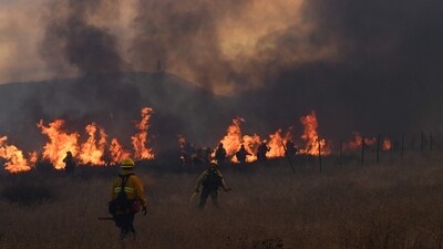 A firefighting crew walks towards flames as a plume of smoke from the Hughes Fire fills the sky in Castaic, a northwestern part of Los Angeles, California, on January 22, 2025. Evacuations were ordered for 19,000 people all around the lake, which sits around 35 miles north of Los Angeles, and close to the city of Santa Clarita. (Photo by Robyn Beck / AFP) (AFP) A firefighting crew walks towards flames as a plume of smoke from the Hughes Fire fills the sky in Castaic, a northwestern part of Los Angeles, California, on January 22, 2025. Evacuations were ordered for 19,000 people all around the lake, which sits around 35 miles north of Los Angeles, and close to the city of Santa Clarita. (Photo by Robyn Beck / AFP) (AFP)