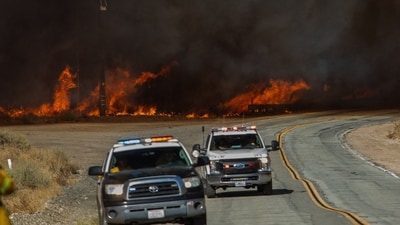 As flames raced up hilltops and down into forested canyons, a 48-kilometer section of Interstate 5, a key north-south route, was blocked. In pic: A fire truck and highway atrol cars back away on Lake Hughes road as flames from the Hughes Fire engulf a hillside in Castaic, a northwestern neighborhood of Los Angeles County, California, (AFP/Apu GOMES ) As flames raced up hilltops and down into forested canyons, a 48-kilometer section of Interstate 5, a key north-south route, was blocked. In pic: A fire truck and highway atrol cars back away on Lake Hughes road as flames from the Hughes Fire engulf a hillside in Castaic, a northwestern neighborhood of Los Angeles County, California, (AFP/Apu GOMES )