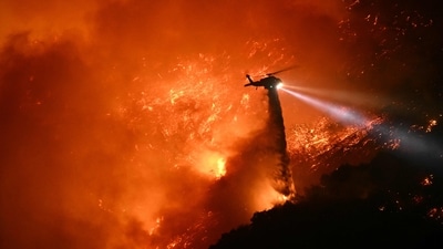 A fire fighting helicopter drops water as the Palisades fire grows near the Mandeville Canyon neighborhood and Encino, California, on January 11, 2025. (AFP) A fire fighting helicopter drops water as the Palisades fire grows near the Mandeville Canyon neighborhood and Encino, California, on January 11, 2025. (AFP)