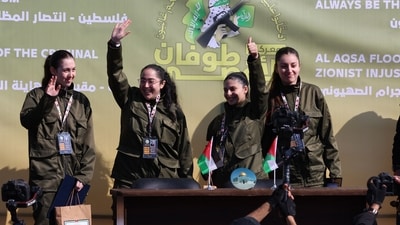 Four Israeli hostages wave on a stage before Hamas fighters hand them over to a team from the Red Cross in Gaza City on January 25, 2025. (AFP) Four Israeli hostages wave on a stage before Hamas fighters hand them over to a team from the Red Cross in Gaza City on January 25, 2025. (AFP)