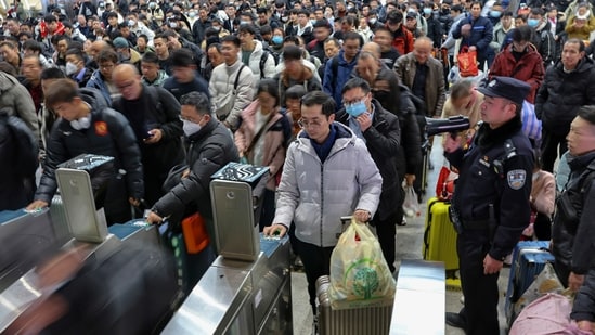A policeman stands watching travellers line up to catch their trains at the departure hall of a railway station ahead of the Lunar New Year in Nantong in east China's Jiangsu province. (AP)