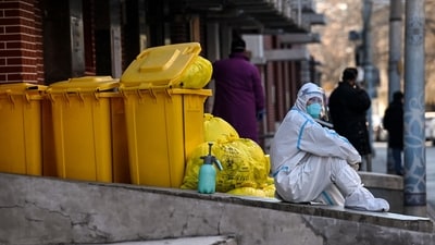 A worker wearing personal protective equipment (PPE) sits next to waste material outside a fever clinic amid the Covid-19 pandemic in Beijing on December 19. (Noel Celis / AFP) A worker wearing personal protective equipment (PPE) sits next to waste material outside a fever clinic amid the Covid-19 pandemic in Beijing on December 19. (Noel Celis / AFP)