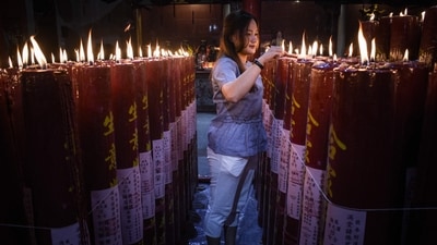 A woman lights a prayer candle at Darma Ramsi Temple to mark the Chinese Lunar New Year in Bandung, West Java, on January 29, 2025. Train stations and airports across many Asian countries have been jam-packed for weeks as millions returned home to spend the holidays with their loved ones. (AFP)