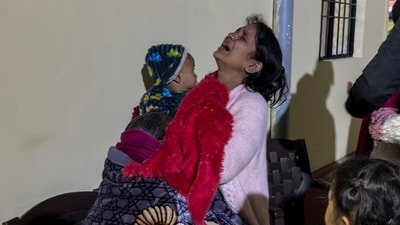Wife of Amit Kumar, a man from Haryana who died in the early morning stampede during the Maha Kumbh, weeps holding her child outside a mortuary in Prayagraj on Wednesday. (AP)