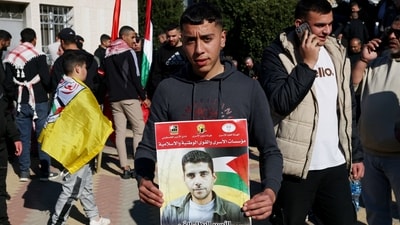 A Palestinian youth holds a portrait of Zakaria Zubeidi, a leader of Al-Aqsa Martys Brigades, as people gathered in Ramallah to receive released Palestinian prisoners from Israeli jails in the occupied West Bank as part of a third hostage-prisoner exchange between Israel and Hamas on January 30, 2025. (AFP)