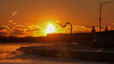 A couple take a walk at sunrise near the icy Oak Street Beach along the shore of Lake Michigan Monday, Jan. 20, 2025, in Chicago (AP/Kiichiro Sato)