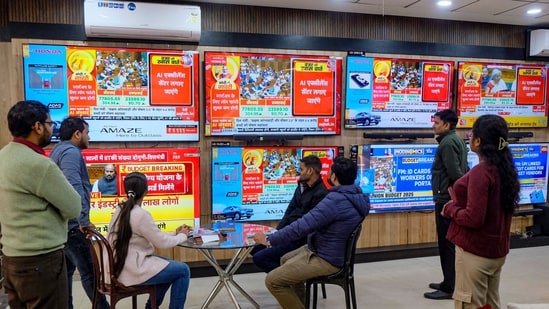 Income tax slabs live: People watch the presentation of Union Budget 2025-26 on television screens at a showroom, in Gurugram, Saturday, Feb. 1, 2025.