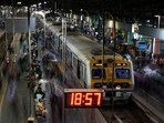 Commuters walk after disembarking from suburban trains as others wait to board at a railway station in Mumbai