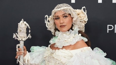 Sierra Ferrell's 2025 Grammys look was truly unforgettable! She wore an extravagant white gown designed by Jeffrey Kelly Designs, which featured massive luminescent sleeves, pearl embellishments throughout, and a matching choker. The overall look was completed with a pearl and flower-adorned headpiece, large pearl chandelier earrings, and a scepter that cleverly held her acceptance speech. (AP) Sierra Ferrell's 2025 Grammys look was truly unforgettable! She wore an extravagant white gown designed by Jeffrey Kelly Designs, which featured massive luminescent sleeves, pearl embellishments throughout, and a matching choker. The overall look was completed with a pearl and flower-adorned headpiece, large pearl chandelier earrings, and a scepter that cleverly held her acceptance speech. (AP)