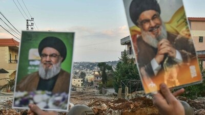 Residents of the southern Lebanese village of Aitaroun lift portraits of Hezbollah's slain leader Hassan Nasrallah (Fadel Itani/AFP) Residents of the southern Lebanese village of Aitaroun lift portraits of Hezbollah's slain leader Hassan Nasrallah (Fadel Itani/AFP)