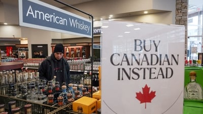 A customer holds a bottle as a sign that reads ''Buy Canadian Instead'' is displayed after the top five US liquor brands were removed from sale at BC Liquor Stores in Vancouver, British Columbia, Canada, on February 2. (Reuters)