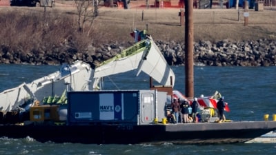 A piece of wreckage is lifted from the water onto a salvage vessel, near the site in the Potomac River of a mid-air collision between an American Airlines jet and a Black Hawk helicopter, at Ronald Reagan Washington National Airport, Tuesday, Feb. 4, 2025, in Arlington, (AP) A piece of wreckage is lifted from the water onto a salvage vessel, near the site in the Potomac River of a mid-air collision between an American Airlines jet and a Black Hawk helicopter, at Ronald Reagan Washington National Airport, Tuesday, Feb. 4, 2025, in Arlington, (AP)