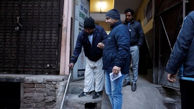 A man uses a cane to exit a polling station after voting in New Delhi’s state assembly elections. So far, Mustafabad recorded the highest turnout at 43%, while Karol Bagh had the lowest at 25.01% (Reuters)