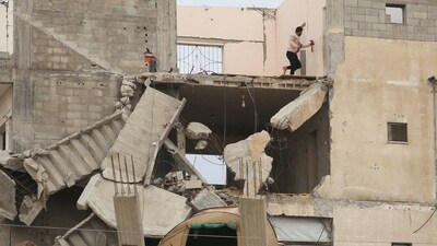 A Palestinian man stands atop a building destroyed during the Israeli offensive, amid a ceasefire between Israel and Hamas, in Khan Younis in the southern Gaza.&nbsp; (REUTERS)