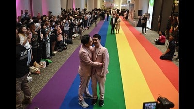 Same-sex couples walk on a rainbow carpet at a marriage registration event at Paragon shopping mall in Bangkok on January 23, 2025. Almost 2,000 same-sex and transgender couples married in Thailand on January 23 as the kingdom's equal marriage law went into effect in a first for Southeast Asia. (Photo by Lillian SUWANRUMPHA / AFP) (AFP)
