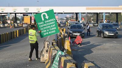A toll worker places signage directing commuters to take a diversion to make a U-turn towards their destination. (Parveen Kumar/HT Photo)