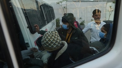 Immigrants, wearing masks, deported from the United States, who were among those who arrived in a US military plane Wednesday in Amritsar, enter a police vehicle at the Ahmedabad airport in Gujarat on Thursday. (AP) Immigrants, wearing masks, deported from the United States, who were among those who arrived in a US military plane Wednesday in Amritsar, enter a police vehicle at the Ahmedabad airport in Gujarat on Thursday. (AP)
