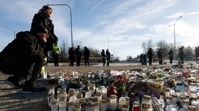 People stand next to candles and flowers placed near the Risbergska school, following a deadly shooting attack at the adult education centre, in Orebro, Sweden (REUTERS/Kuba Stezycki)