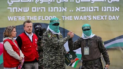Palestinian Hamas militants hold hands as Red Cross members watch during the handover of Or Levy, Eli Sharabi, and Ohad Ben Ami, hostages who have been held in Gaza since the October 7, 2023 attack, as part of a ceasefire and hostages-prisoners swap deal between Hamas and Israel in Deir Al-Balah, central Gaza Strip, February 8, 2025. (REUTERS)