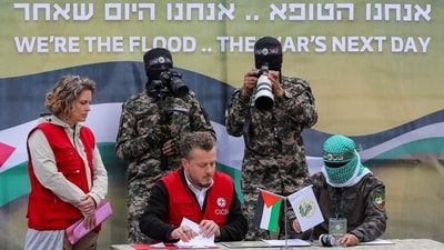 A Palestinian Hamas militant and a Red Cross member sign documents during the handover of Or Levy, Eli Sharabi, and Ohad Ben Ami, who have been held hostage in Gaza since the deadly October 7, 2023 attack. The handover is part of a ceasefire and hostages-prisoners swap agreement between Hamas and Israel in Deir Al-Balah, central Gaza Strip, on February 8, 2025. (REUTERS)