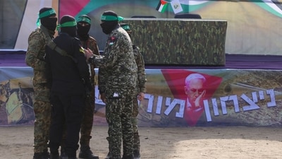 Hamas militants stand in front of a stage before handing over three Israeli hostages to a Red Cross team in Deir el-Balah, central Gaza, on Saturday, as part of the fifth hostage-prisoner exchange during a fragile ceasefire. (AFP) Hamas militants stand in front of a stage before handing over three Israeli hostages to a Red Cross team in Deir el-Balah, central Gaza, on Saturday, as part of the fifth hostage-prisoner exchange during a fragile ceasefire. (AFP)