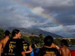 A rainbow forms as members of the Napili Canoe Club run on the beach. (AP)