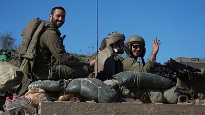 Israeli soldiers wave to the camera from an APC as they cross from the Gaza Strip into Israel. (AP) Israeli soldiers wave to the camera from an APC as they cross from the Gaza Strip into Israel. (AP)