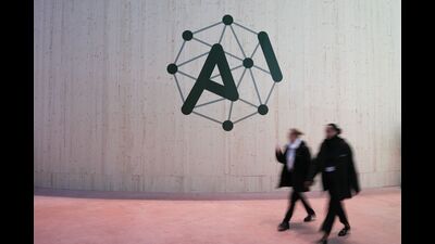 Attendees walk pass an AI Action Summit logo sign at the Grand Palais in Paris, France, on Monday, Feb. 10, 2025. France is set to announce a total of €109 billion in investment in artificial intelligence projects in the country by companies, funds and other sources over the coming years, President Emmanuel Macron said on the eve of a two-day AI Action Summit.. Photographer: Nathan Laine/Bloomberg (Bloomberg)