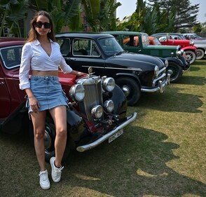 A model stands against vintage cars