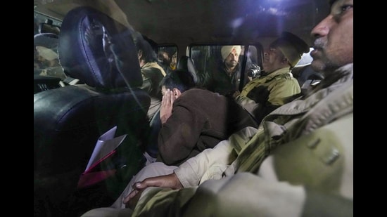 Police personnel take away deported immigrants from the Shri Guru Ramdas Ji International Airport, in Amritsar. (PTI)