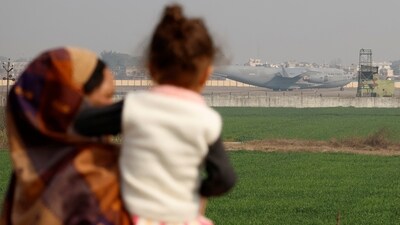 A mother and child look at the US military plane deporting Indian immigrants as it lands in Amritsar earlier this month. (REUTERS)