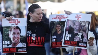 A woman holds posters of Iair Horn, U.S.-Israeli Sagui Dekel-Chen and Russian-Israeli Sasha (Alexandre) Troufanov, hostages who were held in Gaza since the deadly October 7, 2023 attack, and are set to be released as part of a ceasefire deal in Gaza between Hamas and Israel. (Reuters)