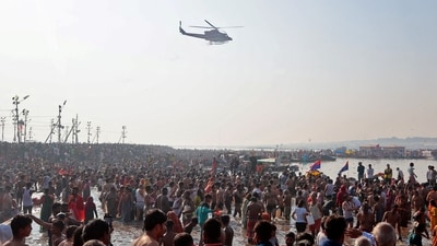 A helicopter drops flower petals on the devotees taking a dip at Sangam in the ongoing Maha Kumbh in Prayagraj. (Reuters)