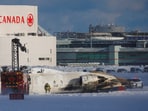 An emergency responder works around an aircraft on a runway, after a plane crash at Toronto Pearson International Airport. 