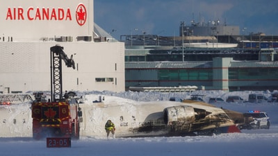 An emergency responder works around an aircraft on a runway, after a plane crash at Toronto Pearson International Airport. (REUTERS)