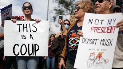 NORTH HOLLYWOOD, CALIFORNIA - FEBRUARY 17: A protester holds a 'This Is A Coup' sign at a rally against the Trump administration during a "Not My President's Day" protest on February 17, 2025 in North Hollywood, California. Protests are being held in cities across the nation on Presidents' Day against what the organizers say are "the anti-democratic and illegal actions of the Trump administration." Mario Tama/Getty Images/AFP (Photo by MARIO TAMA / GETTY IMAGES NORTH AMERICA / Getty Images via AFP) (Getty Images via AFP) NORTH HOLLYWOOD, CALIFORNIA - FEBRUARY 17: A protester holds a 'This Is A Coup' sign at a rally against the Trump administration during a "Not My President's Day" protest on February 17, 2025 in North Hollywood, California. Protests are being held in cities across the nation on Presidents' Day against what the organizers say are "the anti-democratic and illegal actions of the Trump administration." Mario Tama/Getty Images/AFP (Photo by MARIO TAMA / GETTY IMAGES NORTH AMERICA / Getty Images via AFP) (Getty Images via AFP)