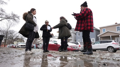 Neighbors talk on their mud covered street Wednesday, Feb. 19, 2025 after a recent water main break caused flooding in Detroit. (AP Photo/Paul Sancya) (AP) Neighbors talk on their mud covered street Wednesday, Feb. 19, 2025 after a recent water main break caused flooding in Detroit. (AP Photo/Paul Sancya) (AP)