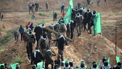 Hundreds of people gathered in the winter cold ahead of the handover at Khan Younis in southern Gaza. Armed Hamas militants in black and camouflage uniforms toured the area. (AFP) Hundreds of people gathered in the winter cold ahead of the handover at Khan Younis in southern Gaza. Armed Hamas militants in black and camouflage uniforms toured the area. (AFP)