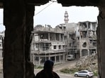 Displaced Syrian Umm Hamza Rifai, 56, looks at the destruction in her neighbourhood from her damaged apartment in Homs' Khaldiyeh district on February 10, 2025, following her return to the central Syrian city in the aftermath of the fall of Bashar al-Assad, after years of living away from their hometown in northern Syria. Since Assad's ouster in December 2024, Rifai and her family have been among thousands of people who have returned to neighbourhoods they fled in Homs during the civil war. (Photo by LOUAI BESHARA / AFP)