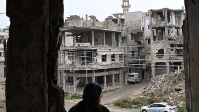 Displaced Syrian Umm Hamza Rifai, 56, looks at the destruction in her neighbourhood from her damaged apartment in Homs' Khaldiyeh district on February 10, 2025, following her return to the central Syrian city in the aftermath of the fall of Bashar al-Assad, after years of living away from their hometown in northern Syria. Since Assad's ouster in December 2024, Rifai and her family have been among thousands of people who have returned to neighbourhoods they fled in Homs during the civil war. (Photo by LOUAI BESHARA / AFP) (AFP)