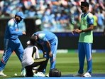A team member checks the leg of India's Mohammed Shami (C) as his team captain Rohit Sharma watches during the ICC Champions Trophy ODI match between India and Pakistan.