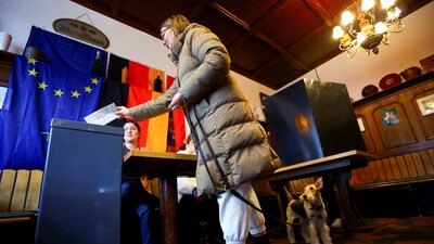 A person votes as their dog stands at a polling station in a pub during the 2025 general election, in Berlin, Germany, (REUTERS)