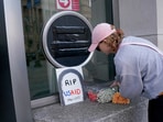 A person leaves flowers, next to a USAID sign which is covered over, at the agency's headquarters in Washington.
