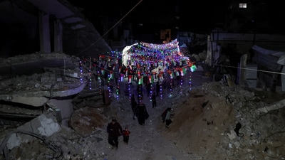 Palestinians walk under decorative lights and near the rubble of buildings, ahead of the holy fasting month of Ramadan, amid a ceasefire between Israel and Hamas, in Khan Younis, in the southern Gaza Strip, February 27, 2025. (REUTERS)