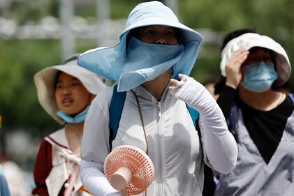 People wearing sun protection gear amid a heatwave walk on a street in Beijing, China. (Reuters)