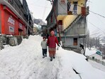 A woman with her child walks through a snowy road in Lahaul Spiti on Thursday. (Aqil Khan /HT) A woman with her child walks through a snowy road in Lahaul Spiti on Thursday. (Aqil Khan /HT)